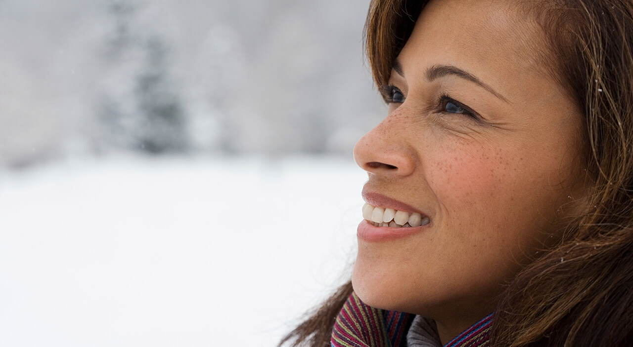 Woman with bright, youthful eyes smiling against a snowy background.