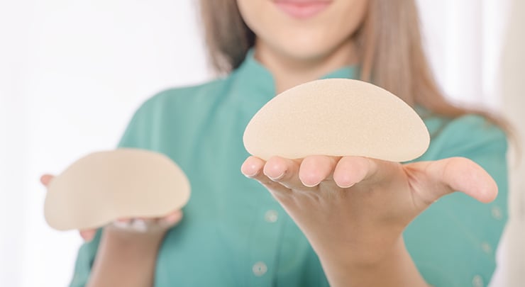 Woman holding breast implants for breast augmentation and lift.