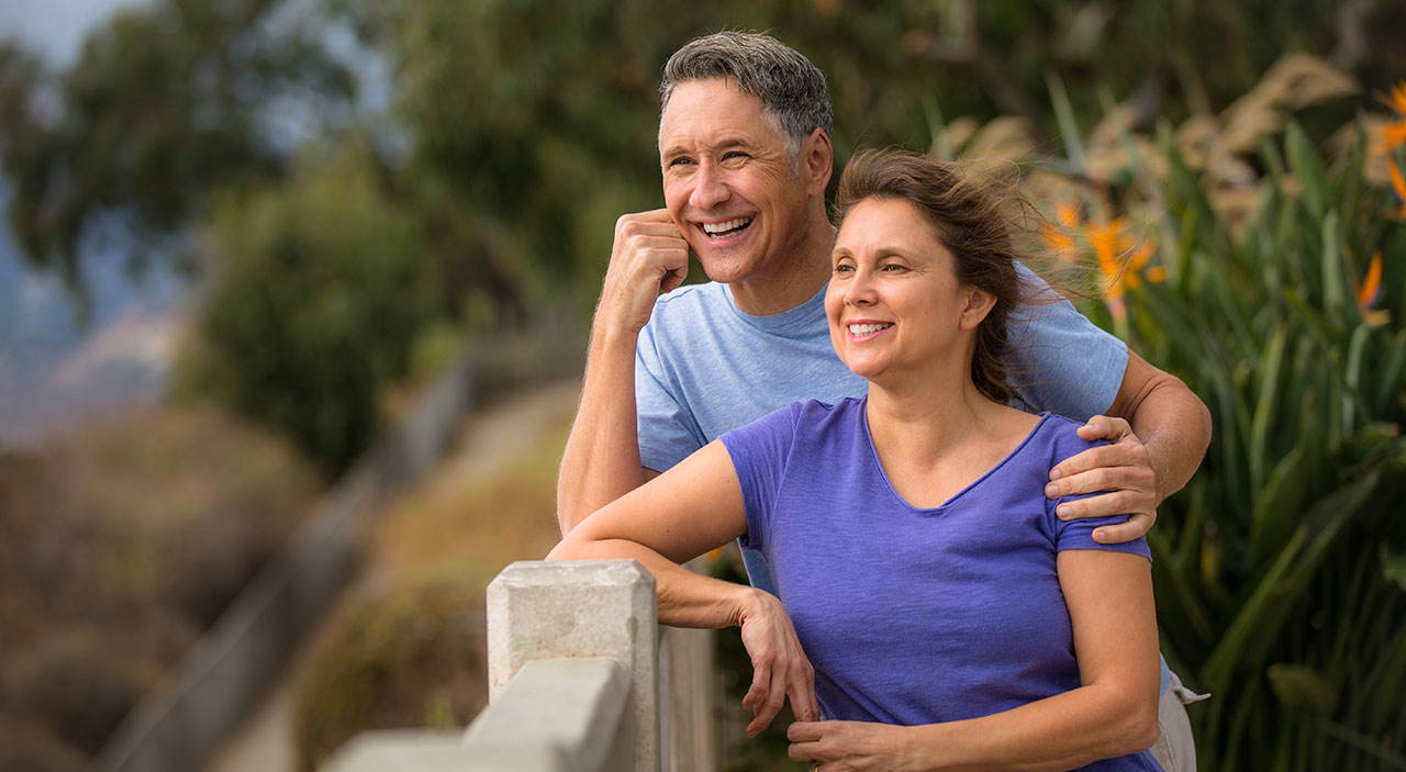 Happy couple enjoying the breeze at the waterfront, looking refreshed and confident.