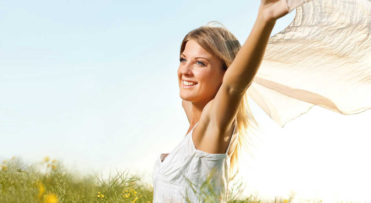 Woman smiling joyfully while holding silk fabric blowing in the breeze.