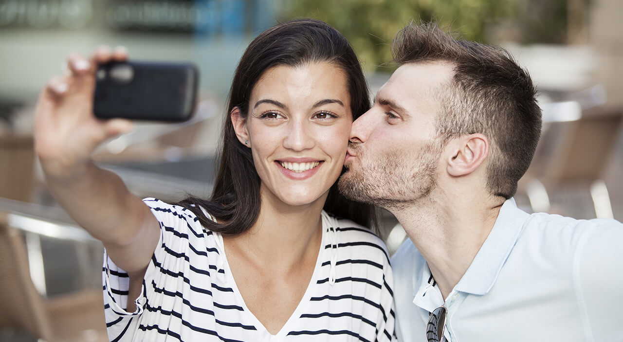 Happy couple, woman taking selfie while preparing for her otoplasty journey.