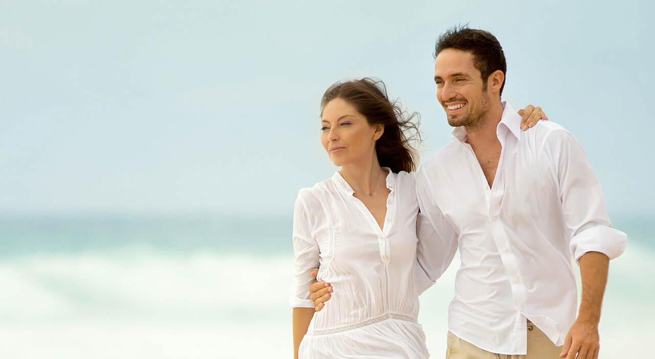 Couple walking on the beach, enjoying a youthful, rejuvenated appearance.
