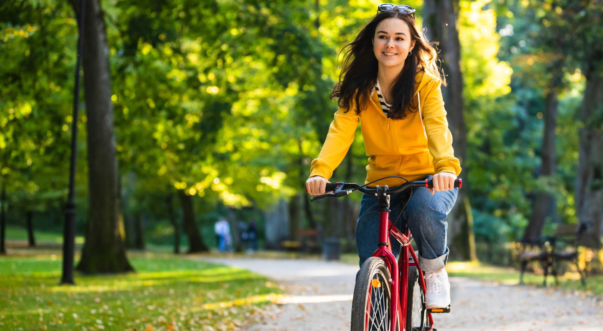 Woman wearing bike helmet sitting on grass beside bike and smiling.