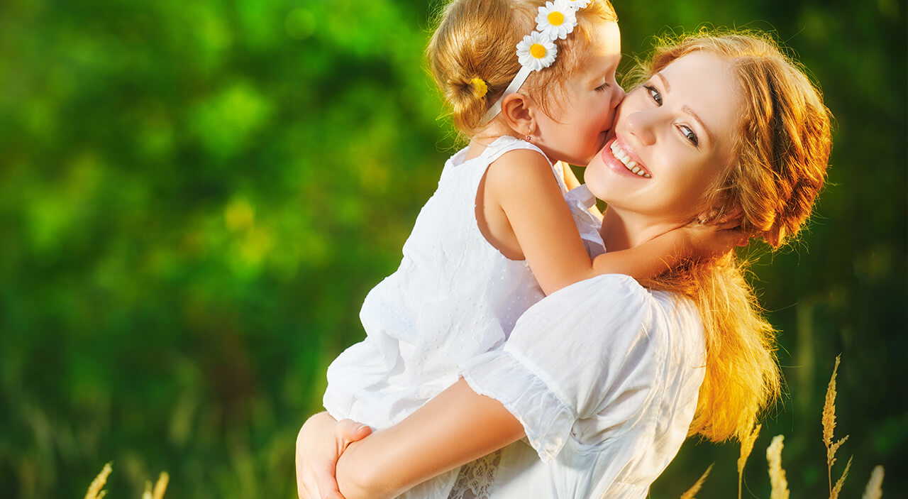 Mother and daughter enjoying time together in a sunlit field.