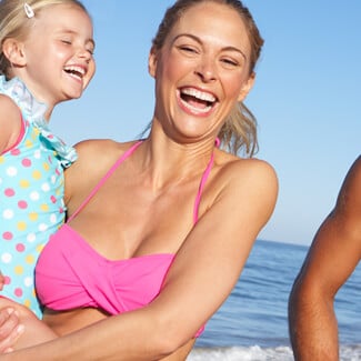 Laughing woman with daughter, husband and son at the beach.