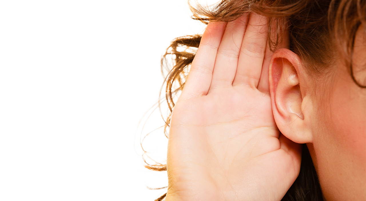 Woman with hand up to her prominent ear.