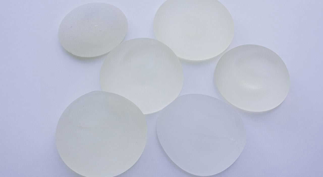 Silicone breast implants lying on grey table.